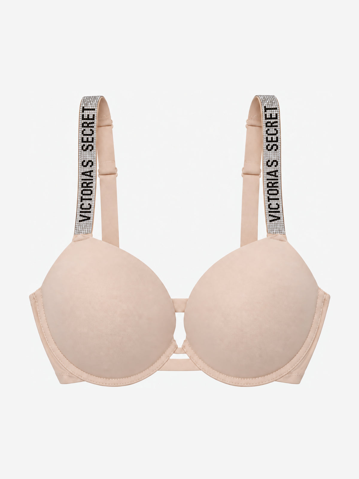 A light beige wireless bra with wide shoulder straps featuring the text 'VICTORIA'S SECRET' in black on a glittery background, shown against a plain light gray background.