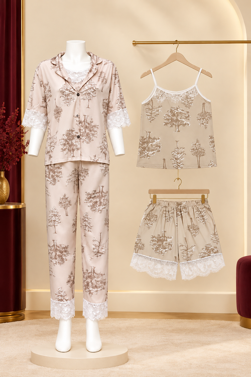 A women's two-piece pajama set displayed on a mannequin, alongside matching camisole and shorts on hangers. The pajama set features a light beige base with a brown toile-style tree pattern and white lace trim.